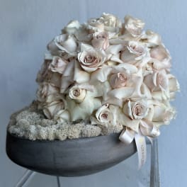 Cream rose bouquet in a black bowl with a ribbon