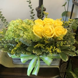 Yellow roses and green hydrangeas in a rectangular box with a ribbon