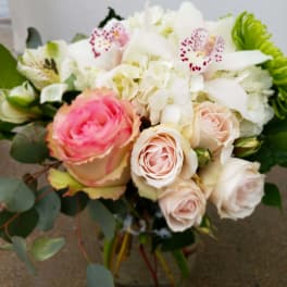 Bouquet of pink and white roses with white orchids in a glass vase