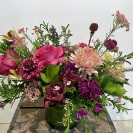 Mixed pink and purple floral arrangement in a green vase