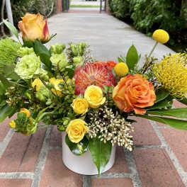 Colorful mixed flower arrangement in a white vase with roses and tropical blooms