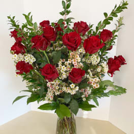 Red roses and white filler flowers in a clear glass vase