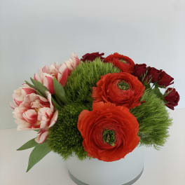 Round bouquet of red and pink flowers in a white box