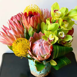 Bouquet of pink protea and green orchids in a blue vase