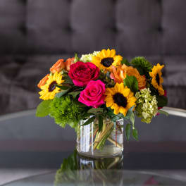 Bouquet of sunflowers and pink roses in a clear glass vase
