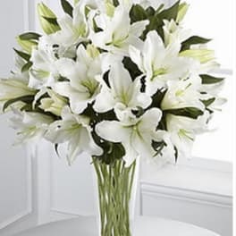 White lilies arranged in a clear glass vase