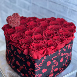 Heart-shaped box filled with red roses and a small heart topper