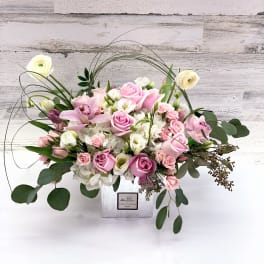 Pink and white floral arrangement in a square white vase