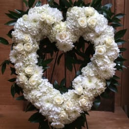 White floral heart wreath with roses and chrysanthemums on a wooden backdrop