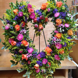 Large floral wreath with orange roses, pink blooms, and purple accents