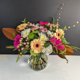 Mixed bouquet of gerbera daisies and chrysanthemums in a glass vase