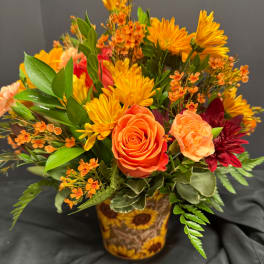Orange roses and yellow daisies in a sunflower-patterned vase