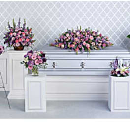 Pink and purple floral funeral casket spray with standing arrangements