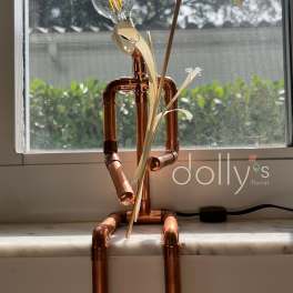 Copper pipe figure with a light bulb head and palm-like leaves