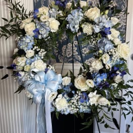 Large floral wreath with white and blue flowers and a pale blue ribbon bow