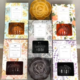 Assorted boxed home fragrance diffusers with floral designs and pumpkin-shaped glass bottles on a shelf