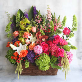 Large mixed flower arrangement in a rectangular basket with pink, orange, purple, and green blooms