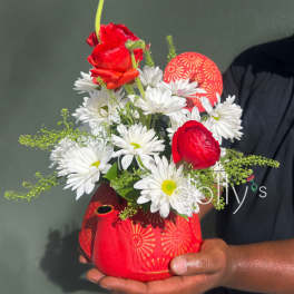 Red and white flower arrangement in a red patterned vase