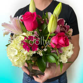 Bouquet of pink roses, lilies, and hydrangeas in a glass vase