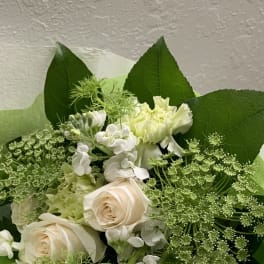 Bouquet of pale roses and white flowers with large green leaves