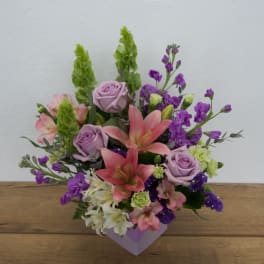 Mixed bouquet with pink lilies, lavender roses, and purple flowers in a lavender box