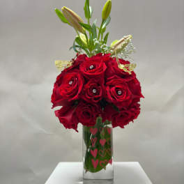 Red roses in a clear glass vase with lily buds and heart decals