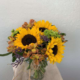 Bouquet of sunflowers and mixed orange flowers in a glass vase