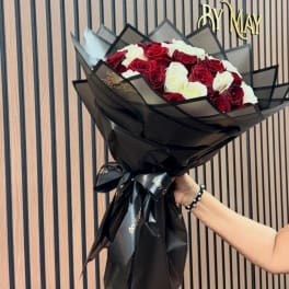 Bouquet of red and white roses wrapped in black paper