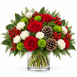 Red roses and white carnations in a glass vase with pinecones and berries