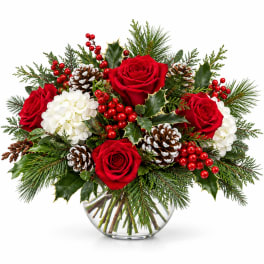 Red roses and white hydrangeas in a glass vase with pinecones and berries
