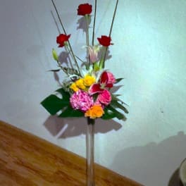 Tall mixed flower arrangement in a clear floor vase