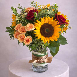 Bouquet of sunflowers and roses in a glass vase with a ribbon