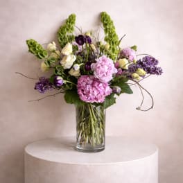 Mixed bouquet of pink, purple, and white flowers in a clear glass vase