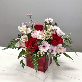 Bouquet of red roses and pink mixed flowers in a red box