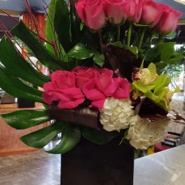 Pink roses and orchids arranged in a tall black vase