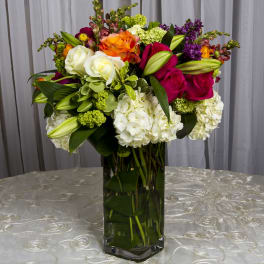 Colorful mixed flower arrangement in a tall glass vase
