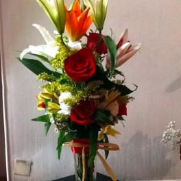 Tall bouquet of lilies and roses in a clear glass vase