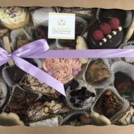Assorted chocolates in a gift box tied with a lavender ribbon.
