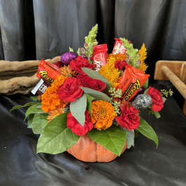 Pumpkin-shaped floral arrangement with candy bars and bright flowers