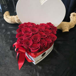Heart-shaped box filled with red roses and a red ribbon