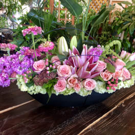 Pink roses and lilies arranged in a low black container
