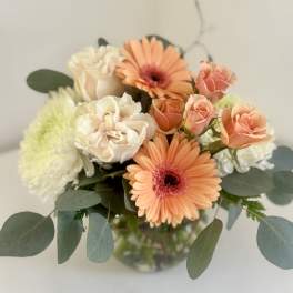 Peach gerberas and cream roses in a glass vase