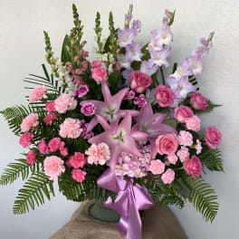 Pink and lavender floral arrangement with lilies, roses, and carnations in a vase