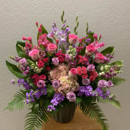 Large pink and purple floral arrangement in a dark vase