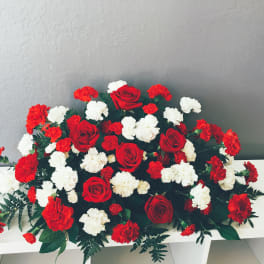 Red roses and red-white carnations arranged low on a white table