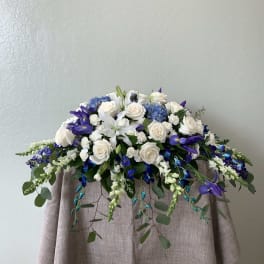White roses and blue-purple flowers arranged on a draped table.