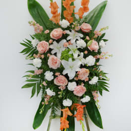 Standing floral spray with peach roses, white lilies, and orange gladiolus