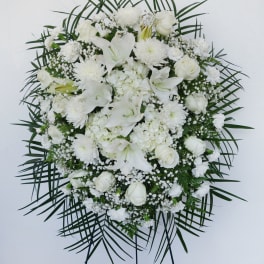 White funeral spray with lilies, roses, and chrysanthemums on a stand