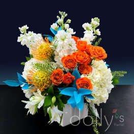 Orange roses and white flowers arranged in a white box with blue accents