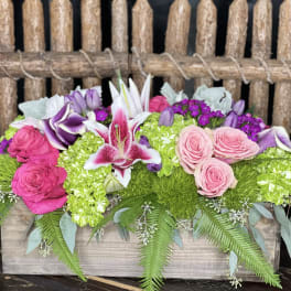 Pink and purple floral arrangement in a wooden box